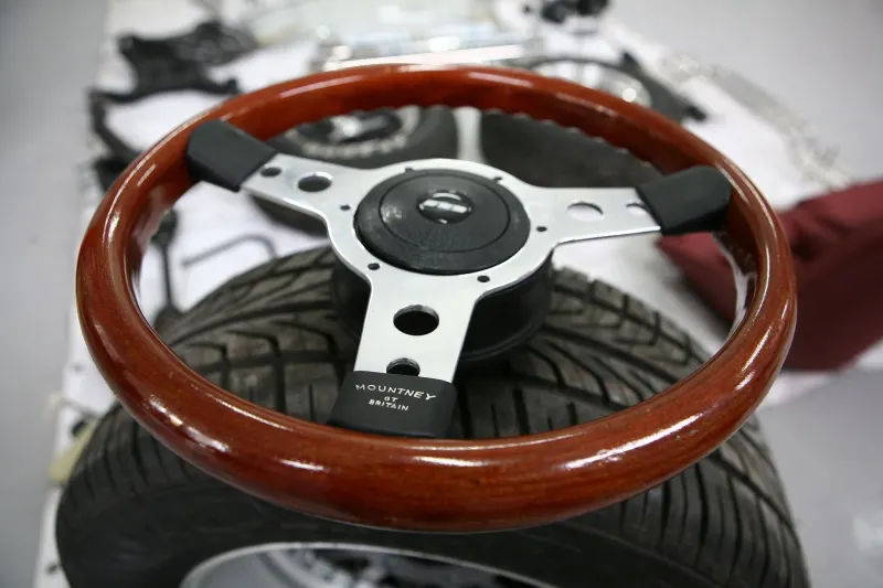 Wood-rimmed classic car steering wheel in a workshop