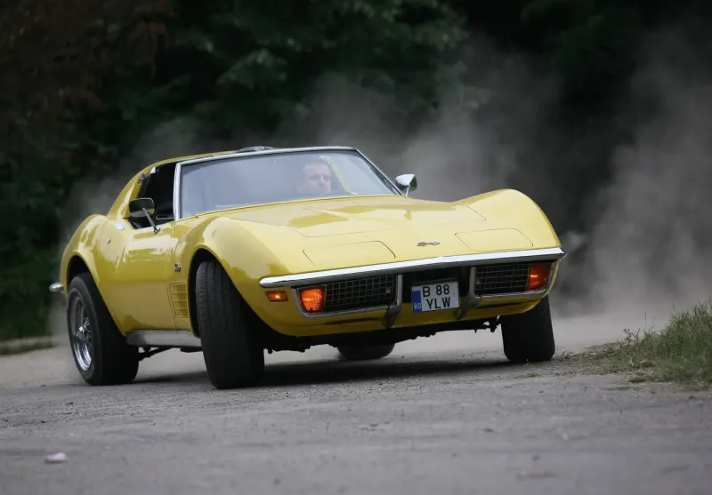 Yellow classic Chevrolet Corvette driving on a country road
